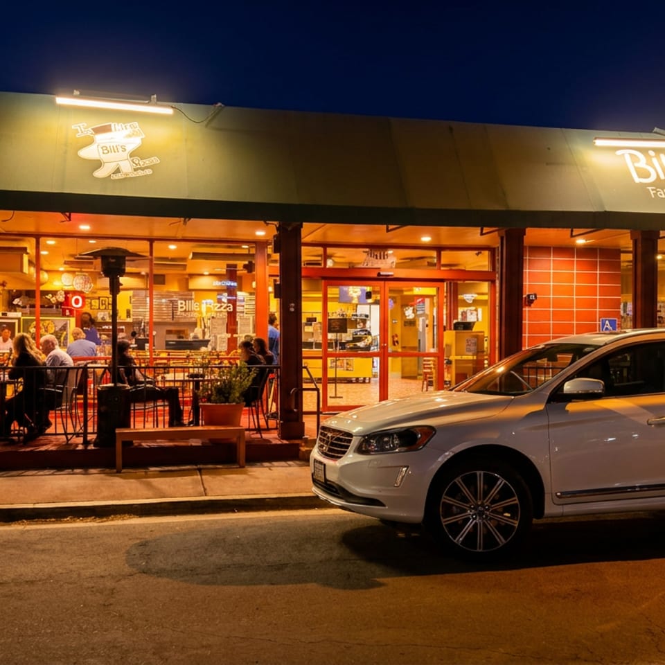 Bill's Pizza restaurant at night with outdoor seating, patrons, and a white car parked in front.